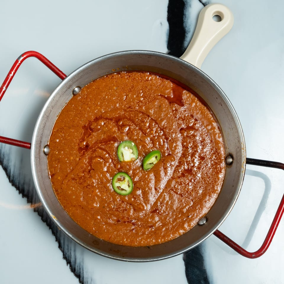 A pan of Ethiopian Shiro Wot, a thick stew, garnished with three green jalapeño slices.