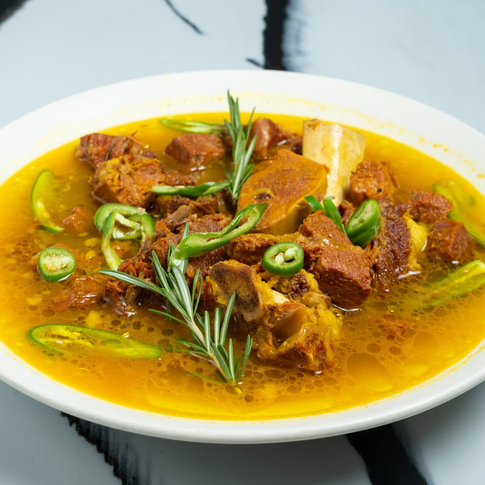 Ethiopian beef stew, or Key Wot, with green peppers and rosemary in a white bowl.