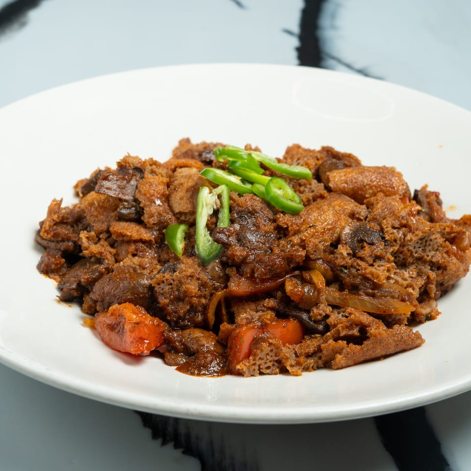 Ethiopian Fitfit, a dish of shredded injera mixed with spicy stew, garnished with green chilies.